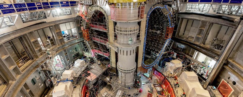 ITER-ingenjören Mathieu Demeyere övervakar lyftet tillsammans med säkerhetsansvarig Clément Vautrin från Framatome. – Den här vinkeln visar komponenterna i en sektormodul: vakuumkärlets 440-tonssektion, termiska skyddspaneler och ytan av en toroidmagnet. Foto: ITER