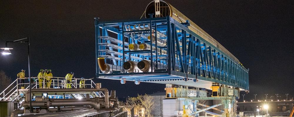 Nyligen lade Stockholm Exergi en 300 ton tung och 92 meter lång rörbro på plats över Lidingövägen i Värtan under en komplex process. Röret blir den centrala förbindelsen mellan Värtaverket och företagets nya bio-CCS-anläggning som nu byggs vid hamnen. Detta sker samtidigt som flera CCS-satsningar läggs ner runtom i Sverige. Foto: Stockholm Energi