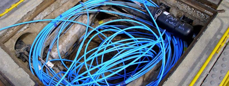 Fiberoptisk kabel och två fibersvetsare i en Telstra-brunn/kanal. Foto: Symbolbild. Wikipedia Commons Lic. Kredit: Bidgee