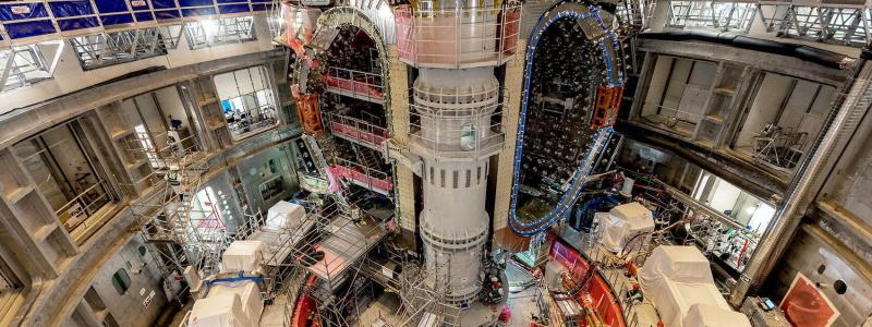 ITER-ingenjören Mathieu Demeyere övervakar lyftet tillsammans med säkerhetsansvarig Clément Vautrin från Framatome. – Den här vinkeln visar komponenterna i en sektormodul: vakuumkärlets 440-tonssektion, termiska skyddspaneler och ytan av en toroidmagnet. Foto: ITER