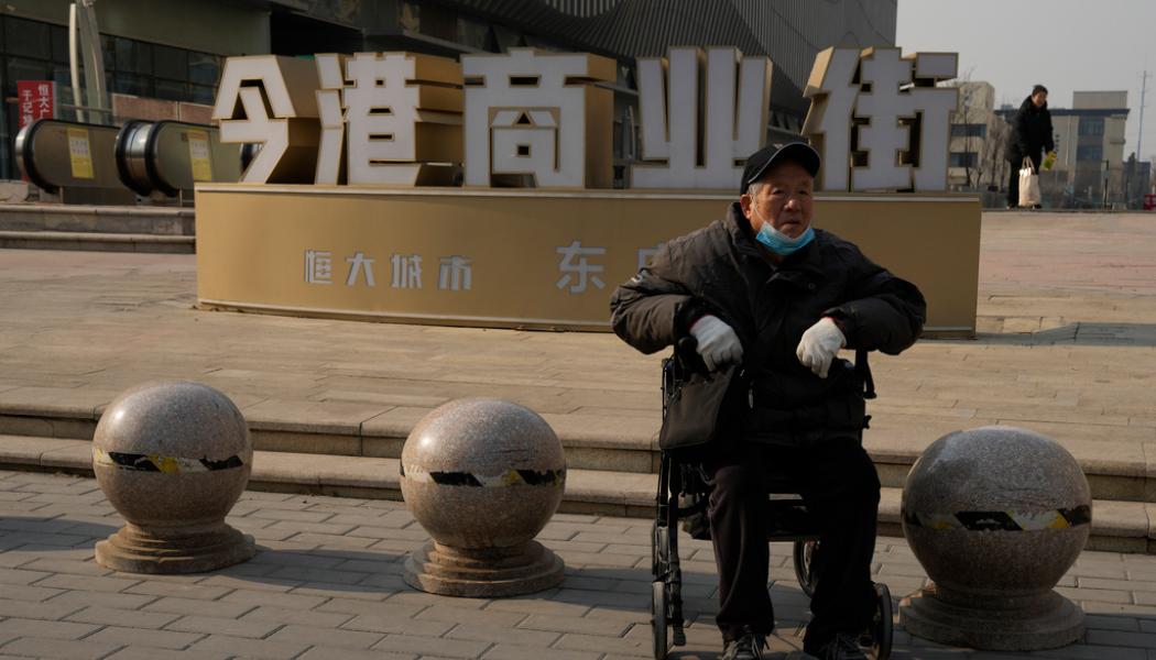 Ng Han Guan/AP/TT: En äldre man utanför ett av det krisdrabbade fastighetsbolaget Evergrandes halvstängda köpcentrum i Peking. Den kinesiska centralbanken meddelar att en viktig femårsränta för bolån sänks för att få stötta branschen. Arkivbild.