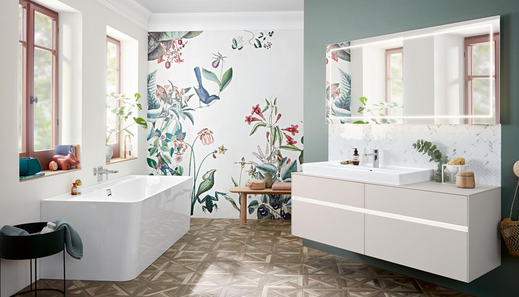En ljus, ombonad miljö från Villeroy & Boch. Generösa Collaro handfat i TitanCeram finns i många former och storlekar. Badkaret i samma kollektion är i akryl 
och kan fås i andra färger. Skarpa linjer i kritvitt mot den blommiga tapeten ger en fräsch känsla. Foto Villeroy & Boch
