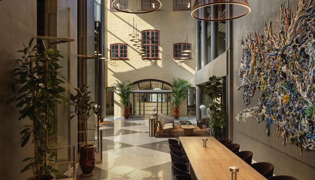 Det stora entréplanet har grafiska rutgolv i svart och vitt, betong, stålkonstruktioner och grå väggar kontrasteras av trämöbler, läder och textilier i chokladbrunt och varma toner.