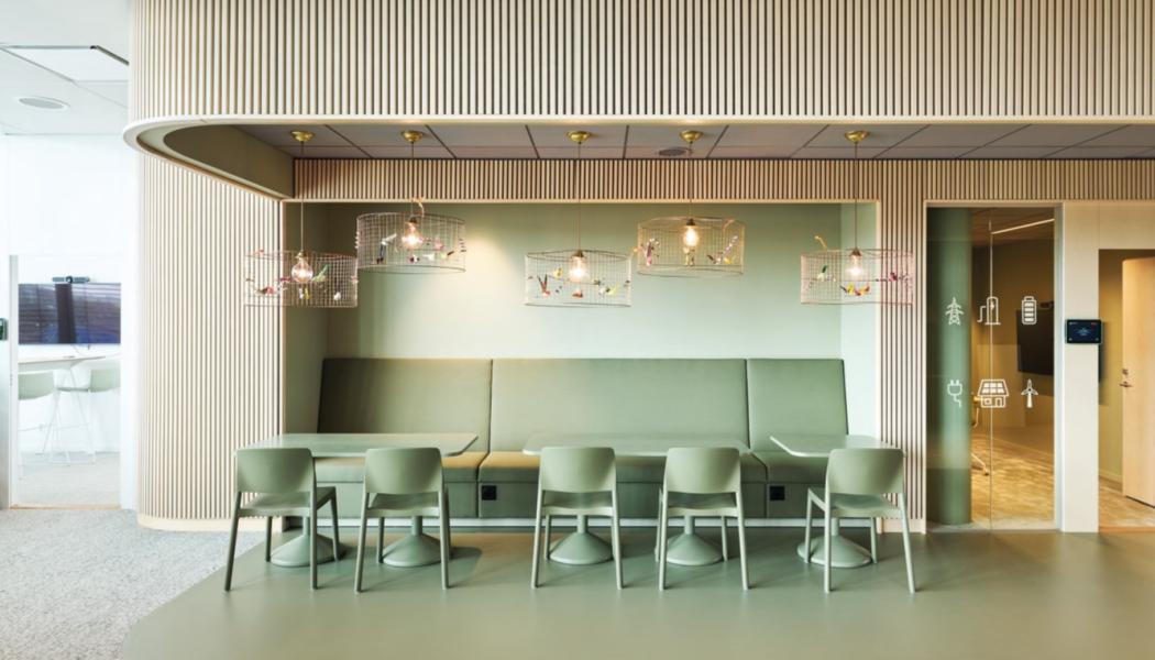 Ljust grön kärna med fast inredning, specialritade soffor i nischen, återbrukad belysning och träribbor i askfanér. Denna coffice area är en öppen yta mellan kärnorna. Där finns pentry och olika sittmöjligheter, genomgående utsikt mot Malmö stadskärna och mot havet. Foto: Mads Frederik