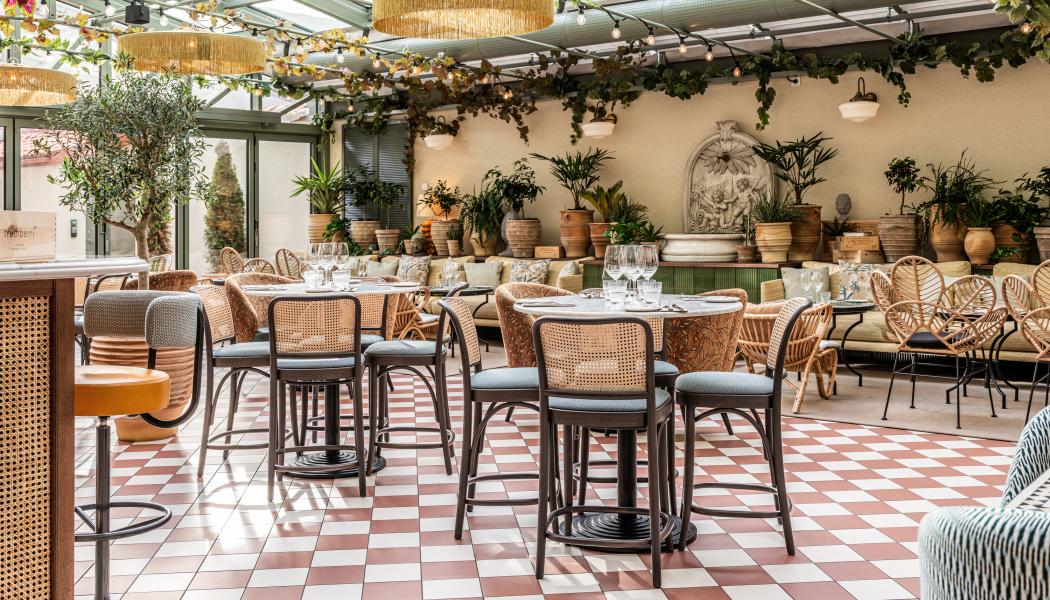 Isolas Ginbar. Ljusfyllt orangeri med glasat tak, terrakottaklinker, fontän och en mix av rotting och klädda stolar i grönskande atmosfär.
Foto: Philip Liljenberg
