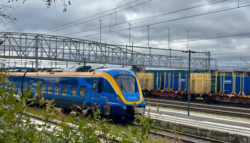 Ett persontåg från Norrtåg passerar bangården i Östersund, med godsvagnar i bakgrunden. Foto: Stina Wickenberg