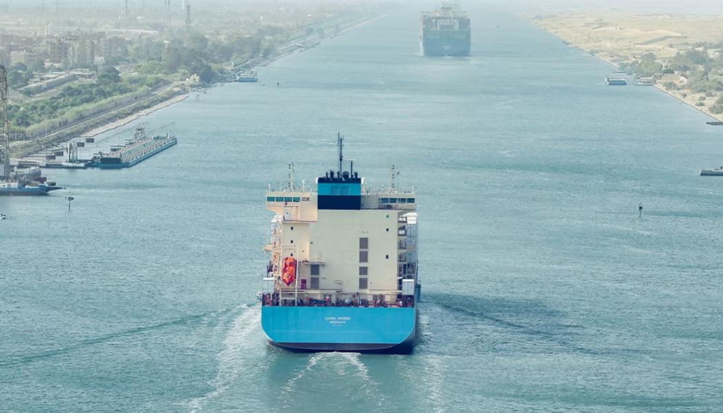 Ett stort containerfartyg med Maersks färger vid ingången till Suezkanalen, vars stränder omges här av grön vegetation. Foto: Maersk