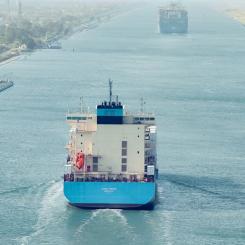 Ett stort containerfartyg med Maersks färger vid ingången till Suezkanalen, vars stränder omges här av grön vegetation. Foto: Maersk